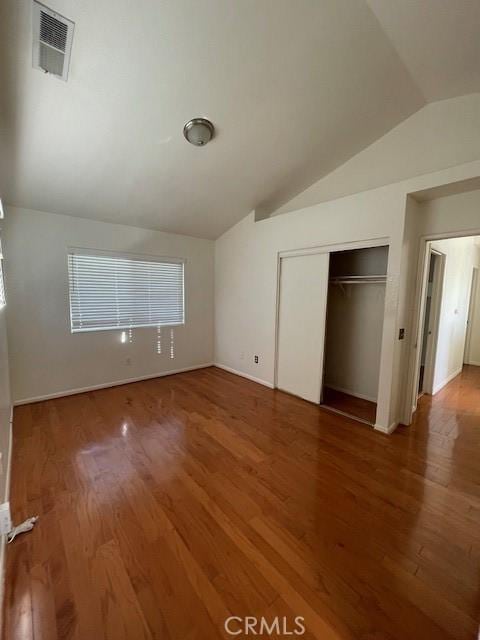 unfurnished bedroom featuring hardwood / wood-style flooring, a closet, and vaulted ceiling