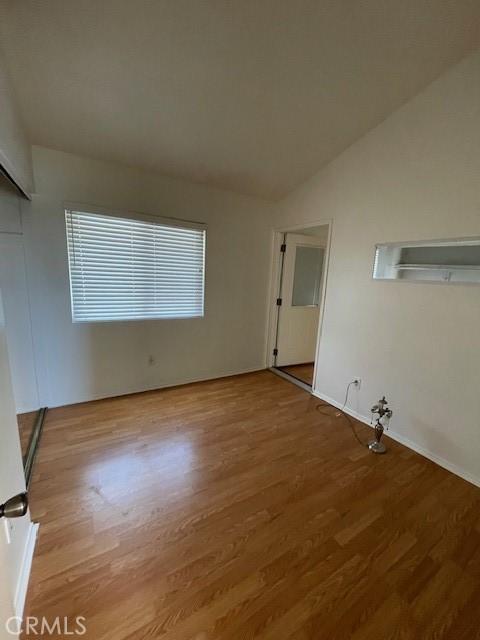 unfurnished room with light hardwood / wood-style flooring and lofted ceiling