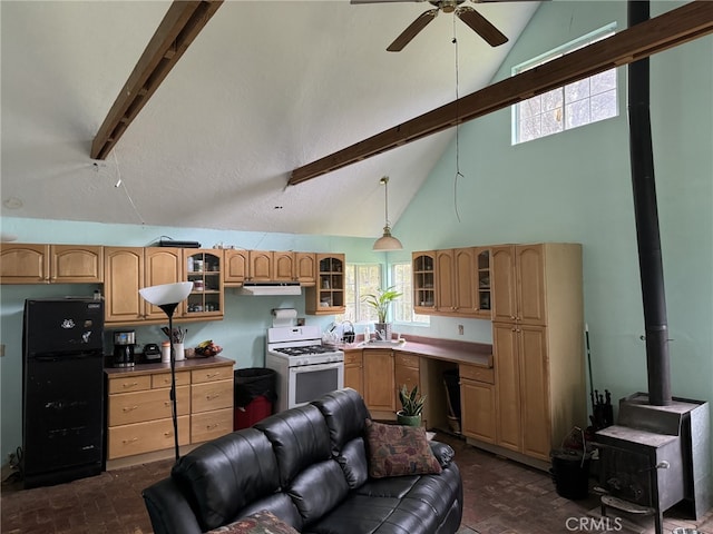 kitchen featuring black fridge, beamed ceiling, a wood stove, gas range gas stove, and high vaulted ceiling