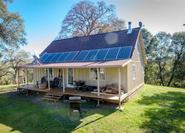 back of property featuring solar panels, a deck, and a lawn