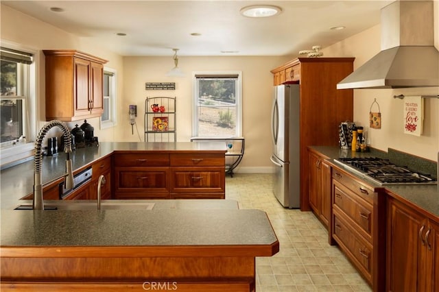 kitchen with appliances with stainless steel finishes, a healthy amount of sunlight, kitchen peninsula, and wall chimney range hood