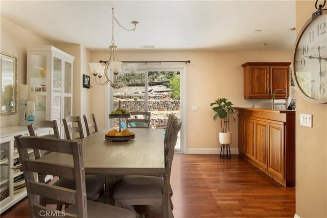 dining room featuring sink, dark hardwood / wood-style flooring, and a notable chandelier