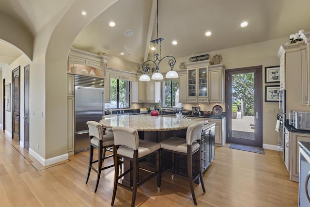 kitchen with a kitchen island, decorative light fixtures, dark stone counters, stainless steel appliances, and cream cabinetry