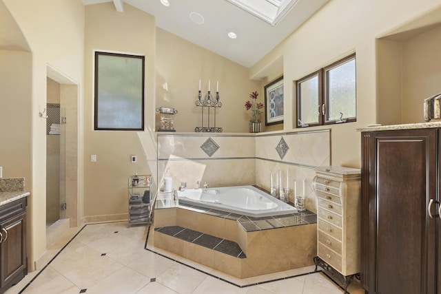 bathroom with vanity, vaulted ceiling with skylight, separate shower and tub, and tile patterned flooring