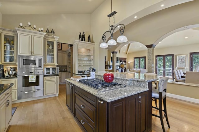 kitchen featuring a kitchen bar, stainless steel appliances, decorative light fixtures, and cream cabinets