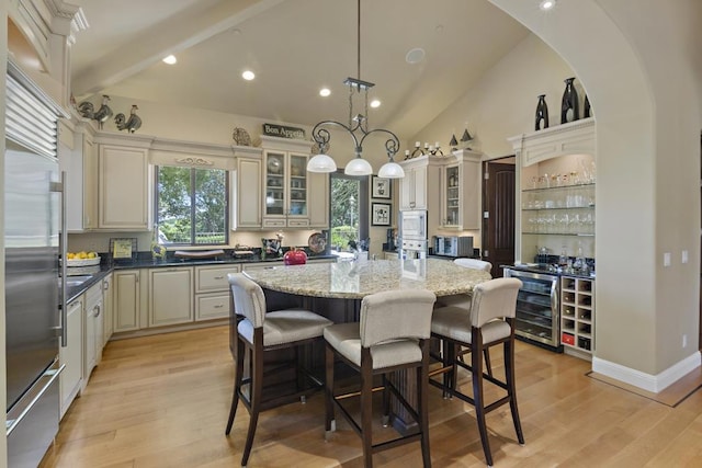 kitchen with beverage cooler, hanging light fixtures, a center island, stainless steel appliances, and cream cabinets