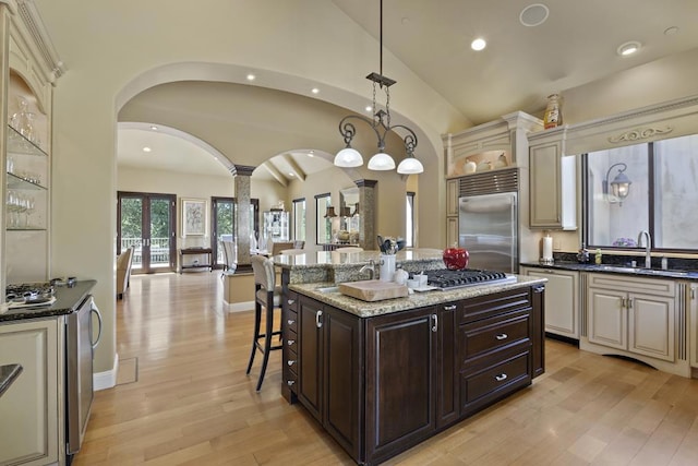 kitchen featuring a kitchen island, decorative light fixtures, sink, a kitchen bar, and stainless steel built in fridge