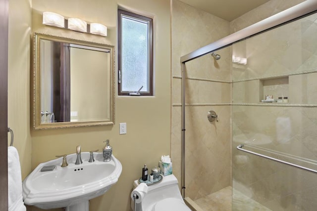 bathroom with toilet, a shower with shower door, and sink