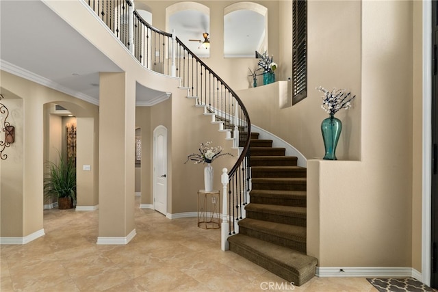 staircase with crown molding and a high ceiling