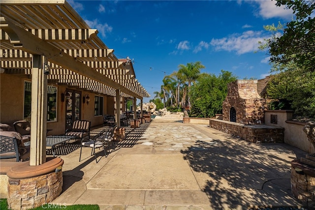 view of patio with an outdoor stone fireplace and a pergola