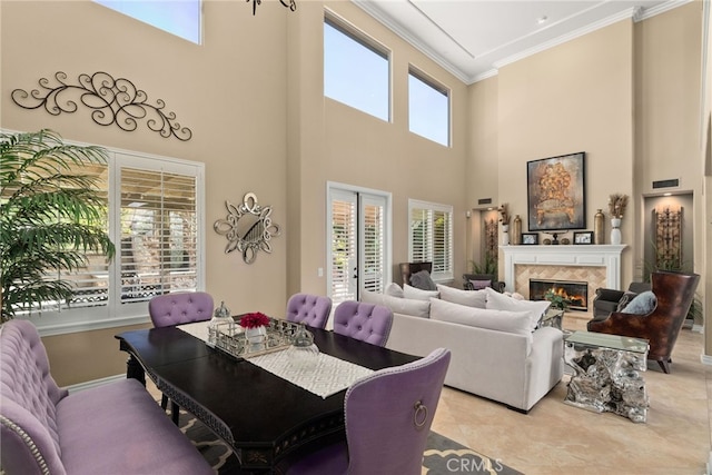 dining area featuring a high end fireplace, a healthy amount of sunlight, and a high ceiling