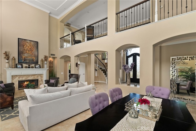 living room with ornamental molding, a high ceiling, and a high end fireplace