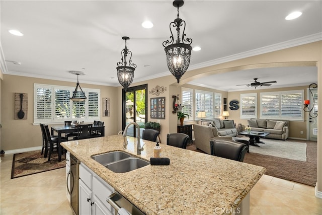 kitchen with white cabinetry, a kitchen island with sink, sink, crown molding, and decorative light fixtures