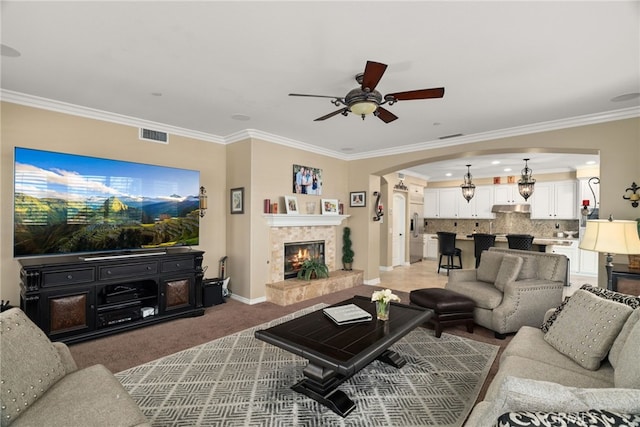 living room featuring crown molding, carpet floors, a fireplace, and ceiling fan