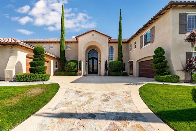 mediterranean / spanish home featuring a front yard and a garage