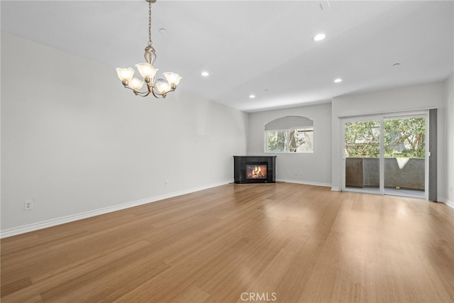 unfurnished living room featuring a chandelier and light hardwood / wood-style floors