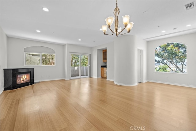 unfurnished living room featuring a chandelier and light hardwood / wood-style flooring