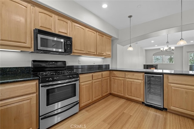 kitchen featuring light brown cabinets, wine cooler, hanging light fixtures, appliances with stainless steel finishes, and light wood-type flooring