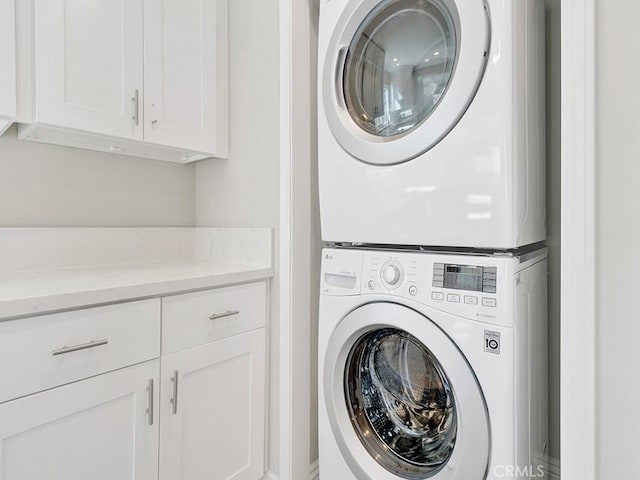 clothes washing area with cabinet space and stacked washer / drying machine