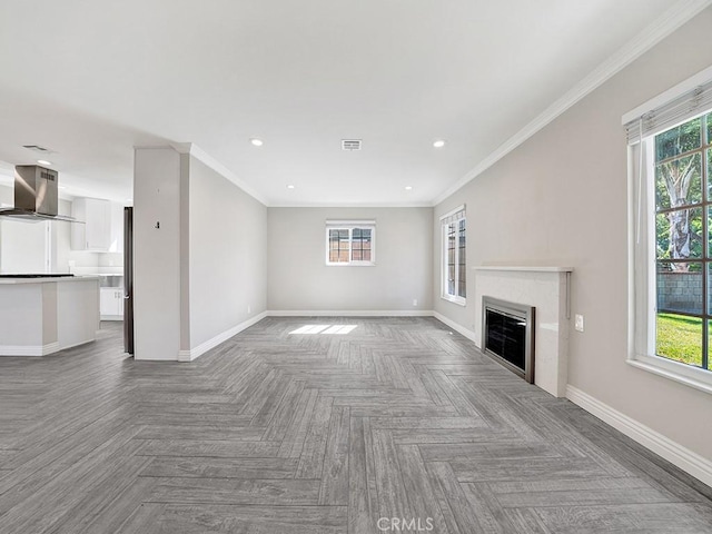 unfurnished living room with visible vents, baseboards, ornamental molding, and a glass covered fireplace