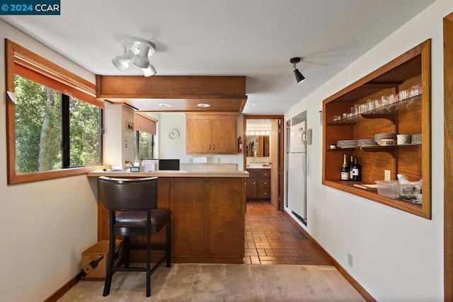 kitchen with dark tile patterned floors, a kitchen bar, and kitchen peninsula