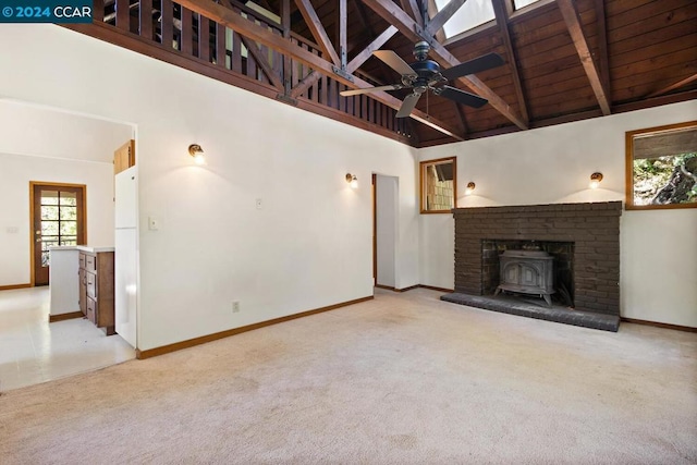 unfurnished living room featuring a wood stove, ceiling fan, beamed ceiling, and high vaulted ceiling