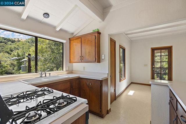 kitchen with white stove, lofted ceiling with beams, and sink