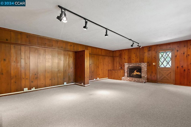 unfurnished living room with carpet, a fireplace, and rail lighting