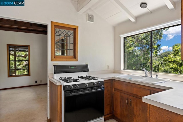 kitchen with vaulted ceiling with beams, gas stove, a healthy amount of sunlight, and sink