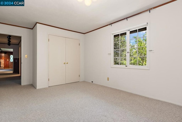 unfurnished bedroom featuring light colored carpet, ornamental molding, and a closet