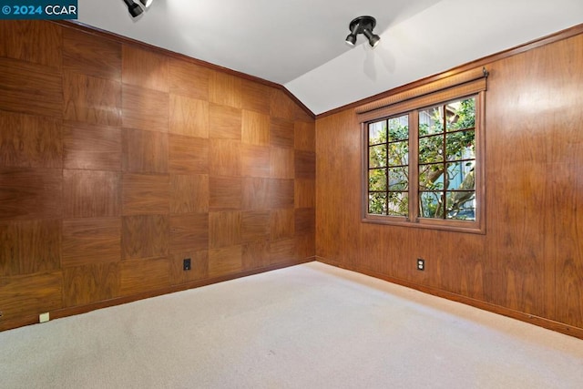 carpeted spare room with wooden walls and vaulted ceiling