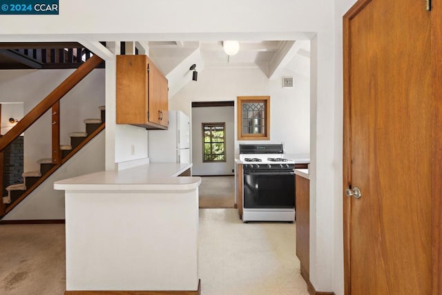 kitchen with beamed ceiling, light carpet, white appliances, and kitchen peninsula