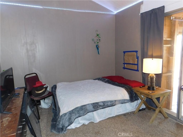 bedroom with carpet floors, lofted ceiling, and wood walls