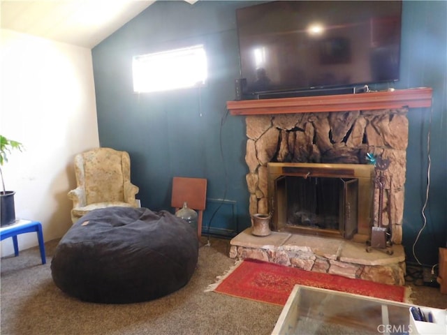 living area featuring carpet, vaulted ceiling, and a stone fireplace