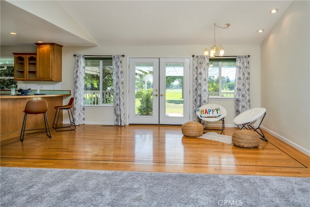 sitting room with light wood-type flooring, lofted ceiling, and a notable chandelier