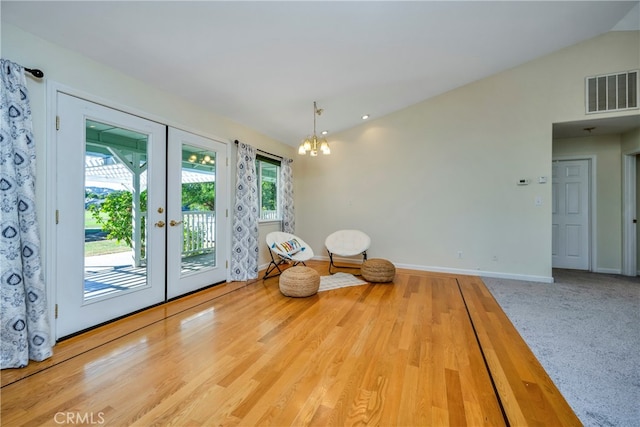 unfurnished room with light hardwood / wood-style flooring, vaulted ceiling, an inviting chandelier, and french doors