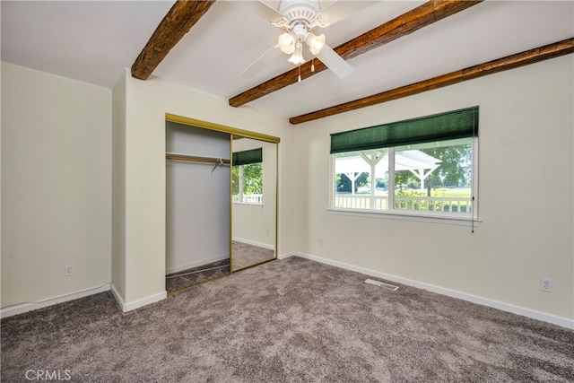 unfurnished bedroom with ceiling fan, beamed ceiling, a closet, and carpet flooring