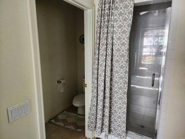 bathroom featuring toilet, tile patterned floors, and a shower with shower door