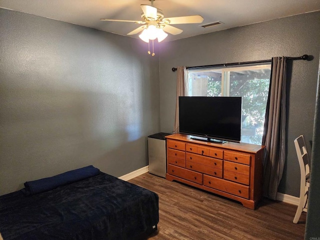 bedroom with stainless steel fridge, dark hardwood / wood-style flooring, and ceiling fan