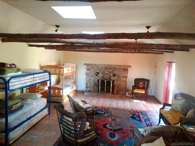 living room with beamed ceiling, a fireplace, and a skylight