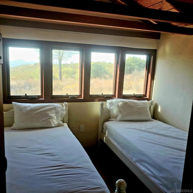 bedroom featuring beamed ceiling, multiple windows, and wooden ceiling