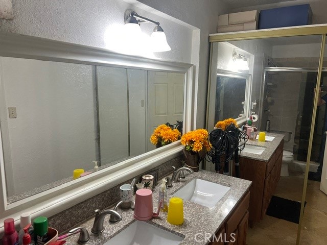 bathroom with a shower with door, vanity, and toilet