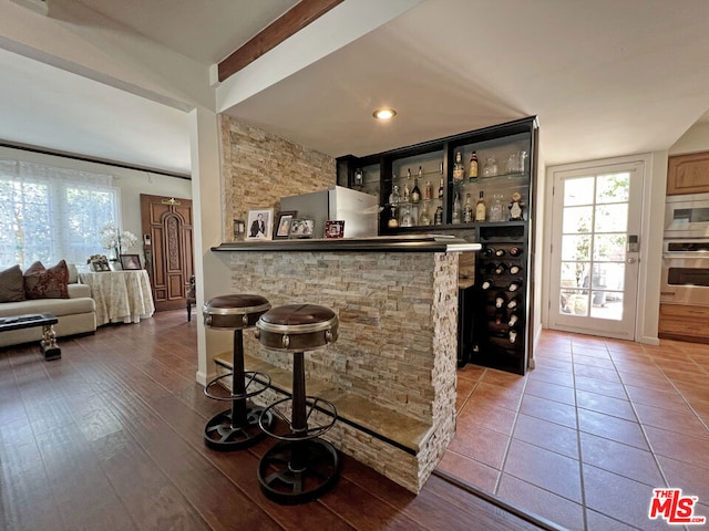 bar featuring appliances with stainless steel finishes, hardwood / wood-style floors, and beam ceiling