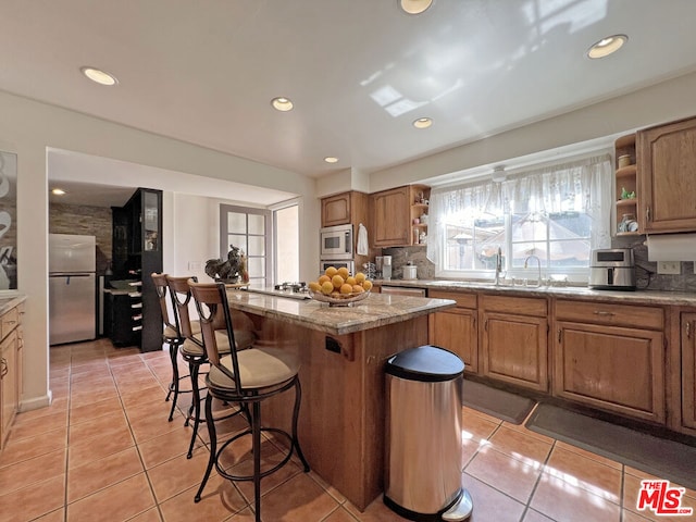 kitchen featuring light stone counters, light tile patterned flooring, appliances with stainless steel finishes, and a center island