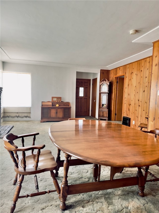 carpeted dining space with wooden walls