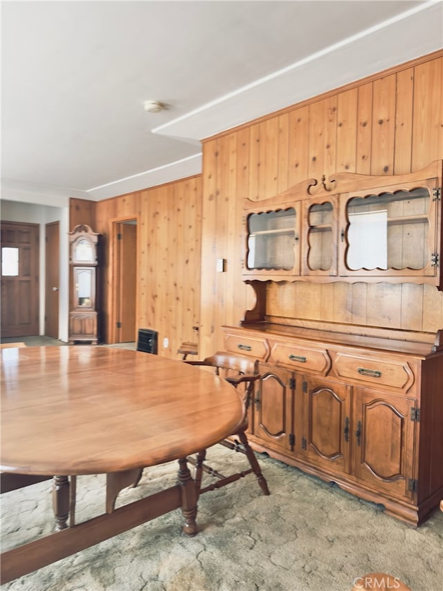 dining area with light carpet and wooden walls