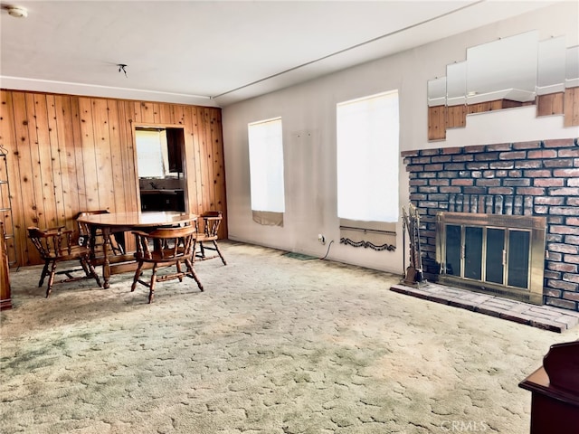 carpeted dining room with wooden walls and a fireplace