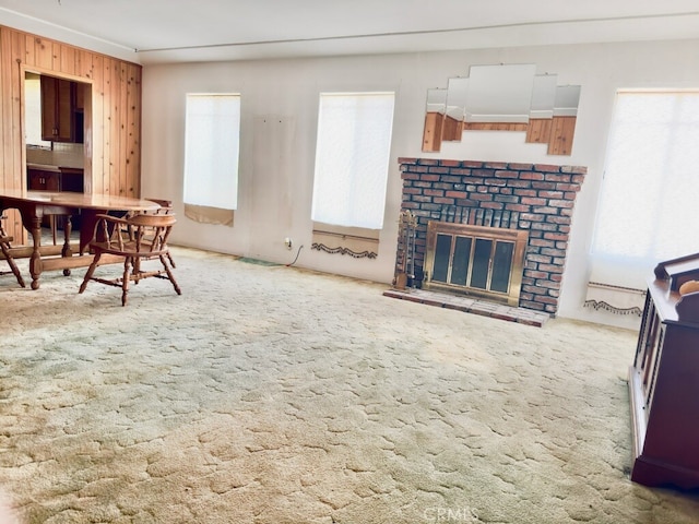 carpeted living room featuring wooden walls and a fireplace