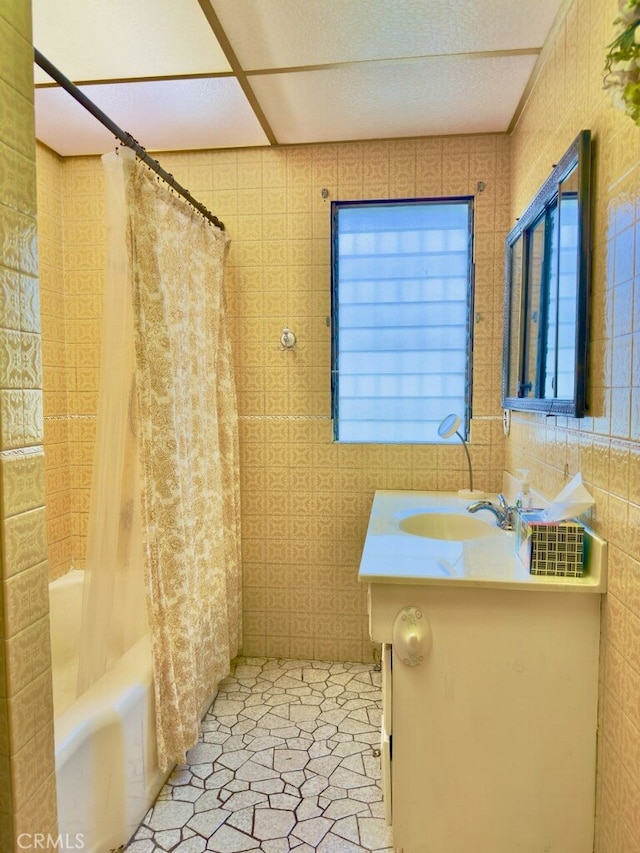 bathroom with vanity, shower / tub combo with curtain, tile patterned floors, and tile walls