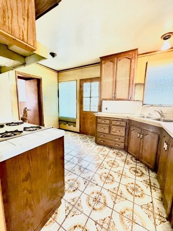 kitchen featuring white gas stovetop, sink, and light tile patterned floors